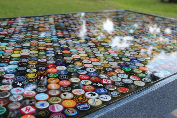 An epoxy table top with a layer of bottle caps embedded inside the resin finish.