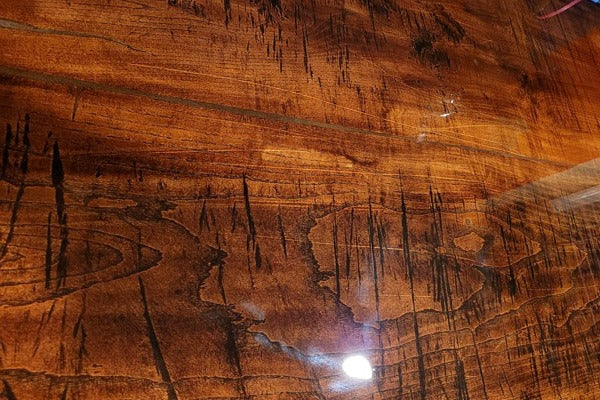 A live-edge wooden epoxy bar top, seen close up to view the smooth, crystal-clear finish.