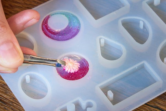 A silicone mold with two of the reservoirs filled with colorful epoxy resin.