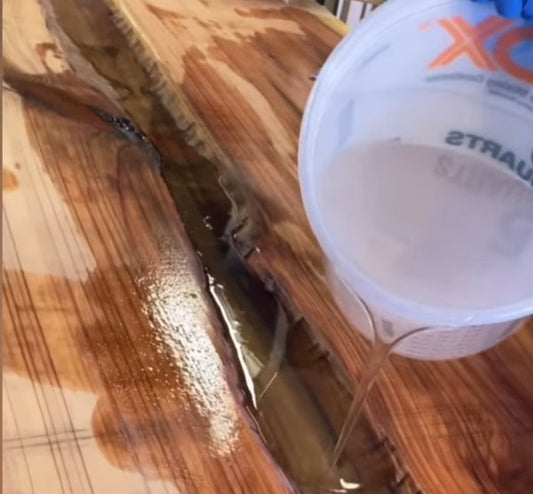 A batch of epoxy resin being poured onto a wooden substrate.