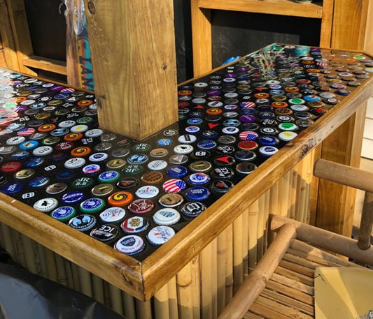 A bottle cap epoxy bar top, made with wood, epoxy resin, and numerous bottle caps that have been embedded within the epoxy.